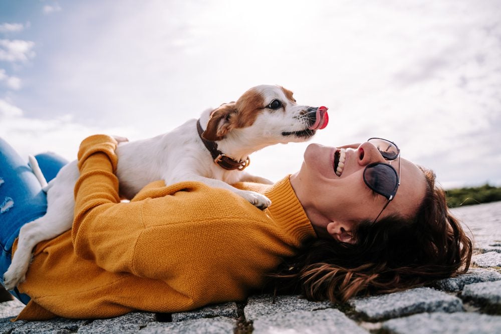 Woman lies down outside with small dog