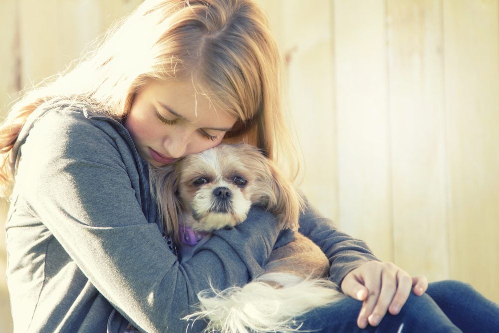 Young blond girl hugs a small dog