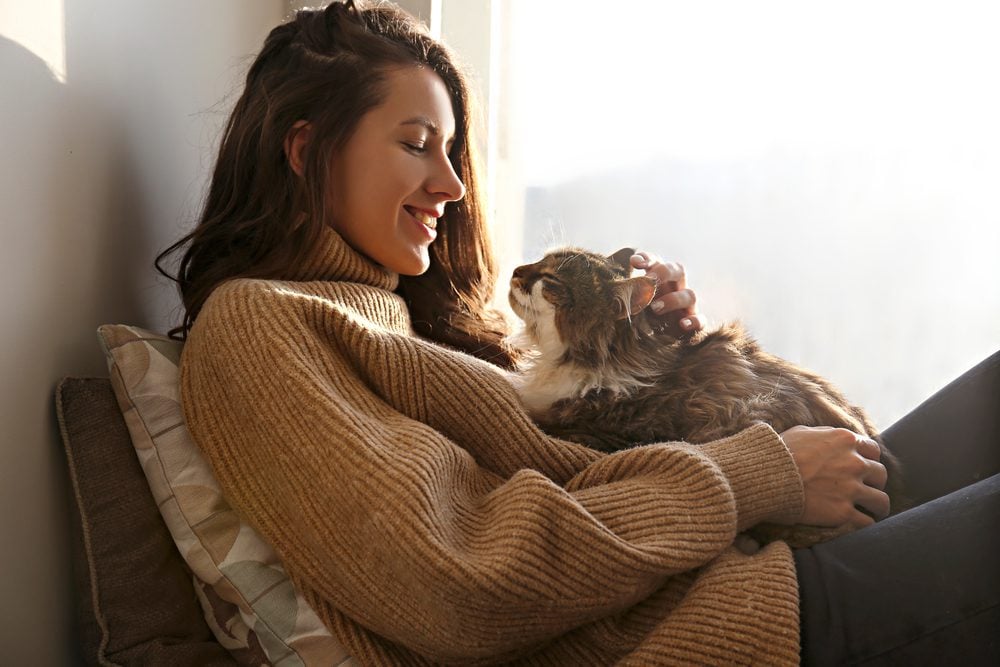 Young woman holding cat on a couch