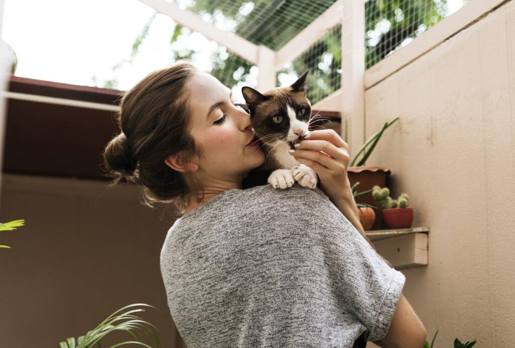 woman hugging kissing cat