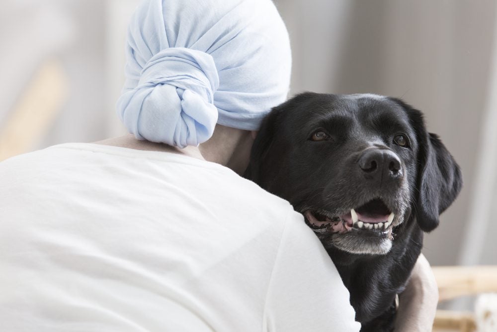 woman hugging black labrador