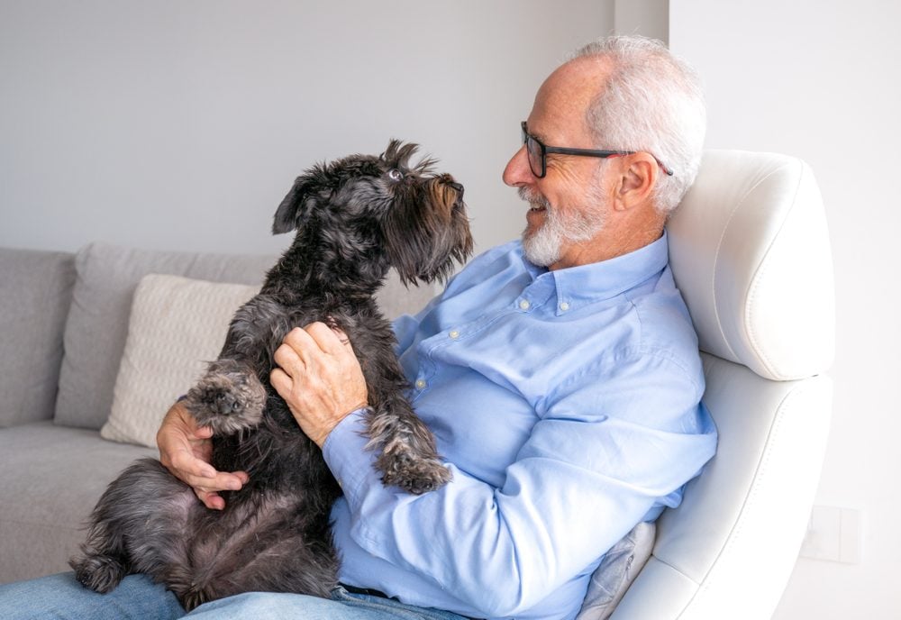 senior man holding support dog inside