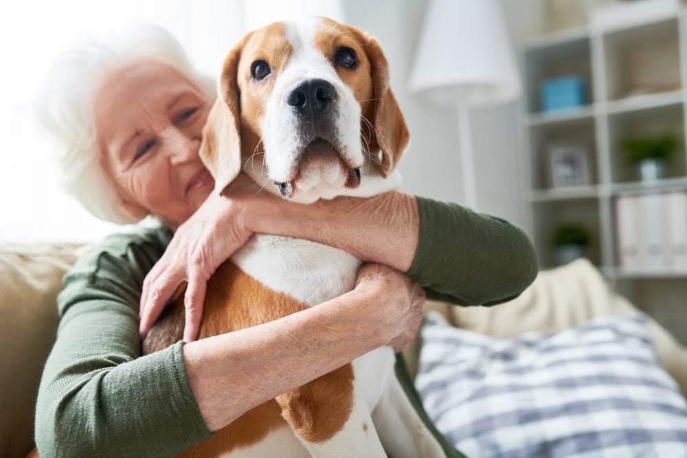 senior woman hugging dog at home