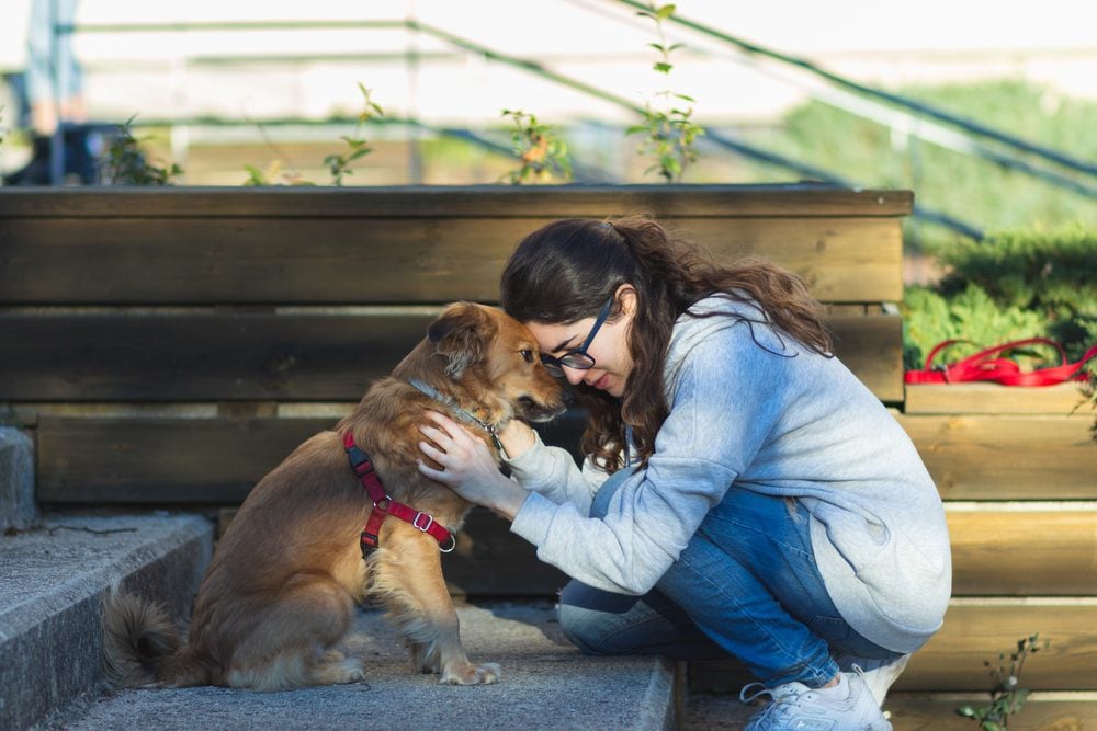 woman cuddles dog on steps