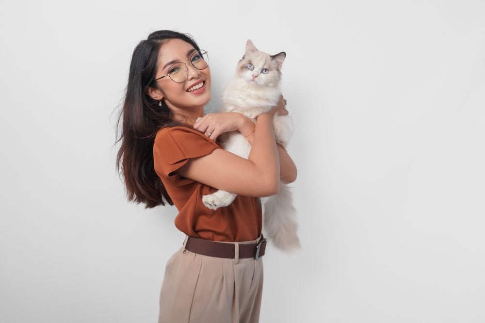 woman in brown shirt holding cat