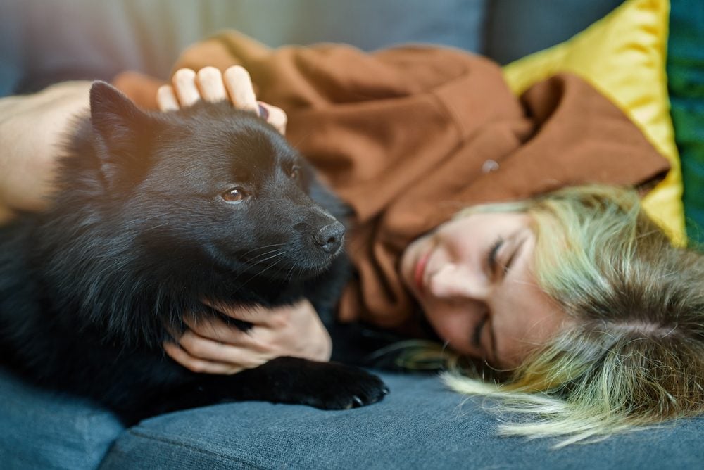 woman lying on couch hugging her dog emotional support animal