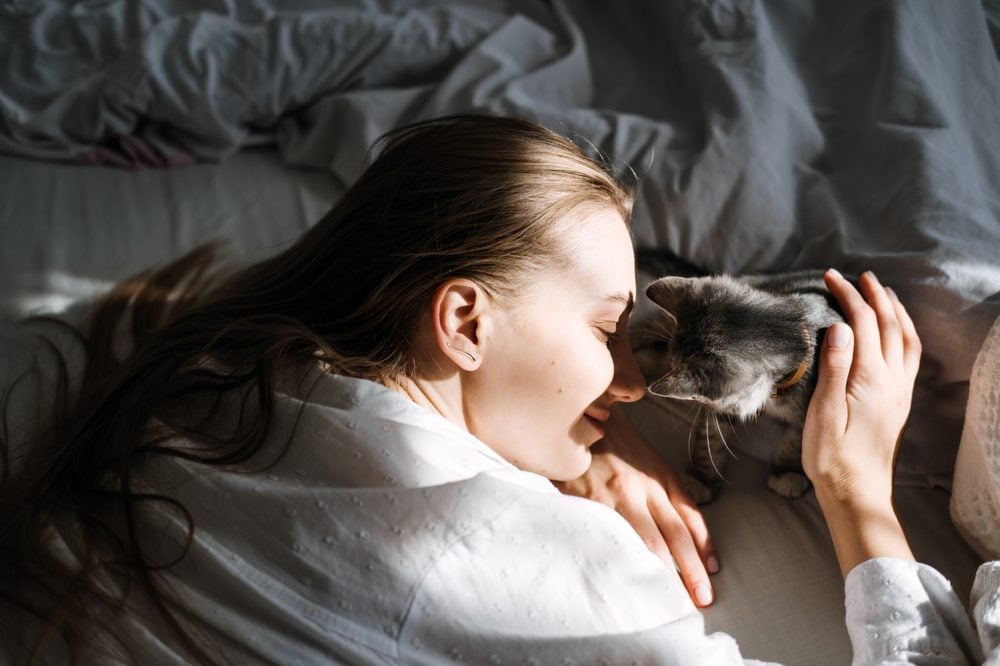 A young woman hugging a cat that meets the emotional support animal requirements.
