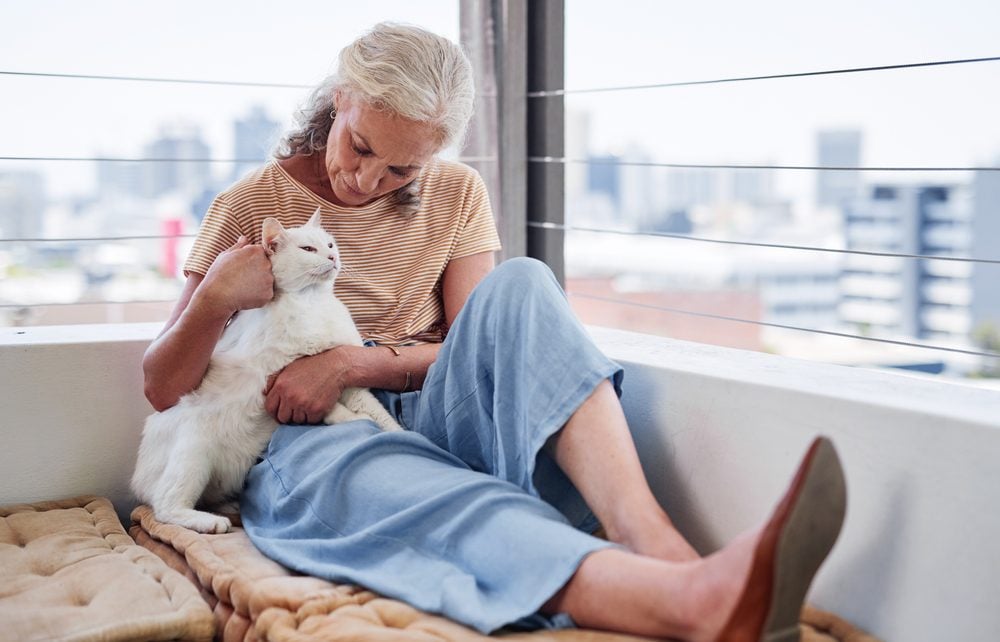 An older woman lovingly holding her emotional support cat on her lap in Birmingham, AL.