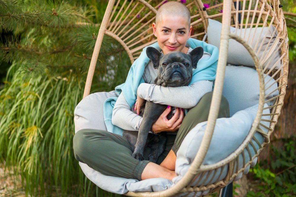 A woman relaxing in an outdoor hanging chair while hugging her emotional support animal (ESA) in Mobile, AL.
