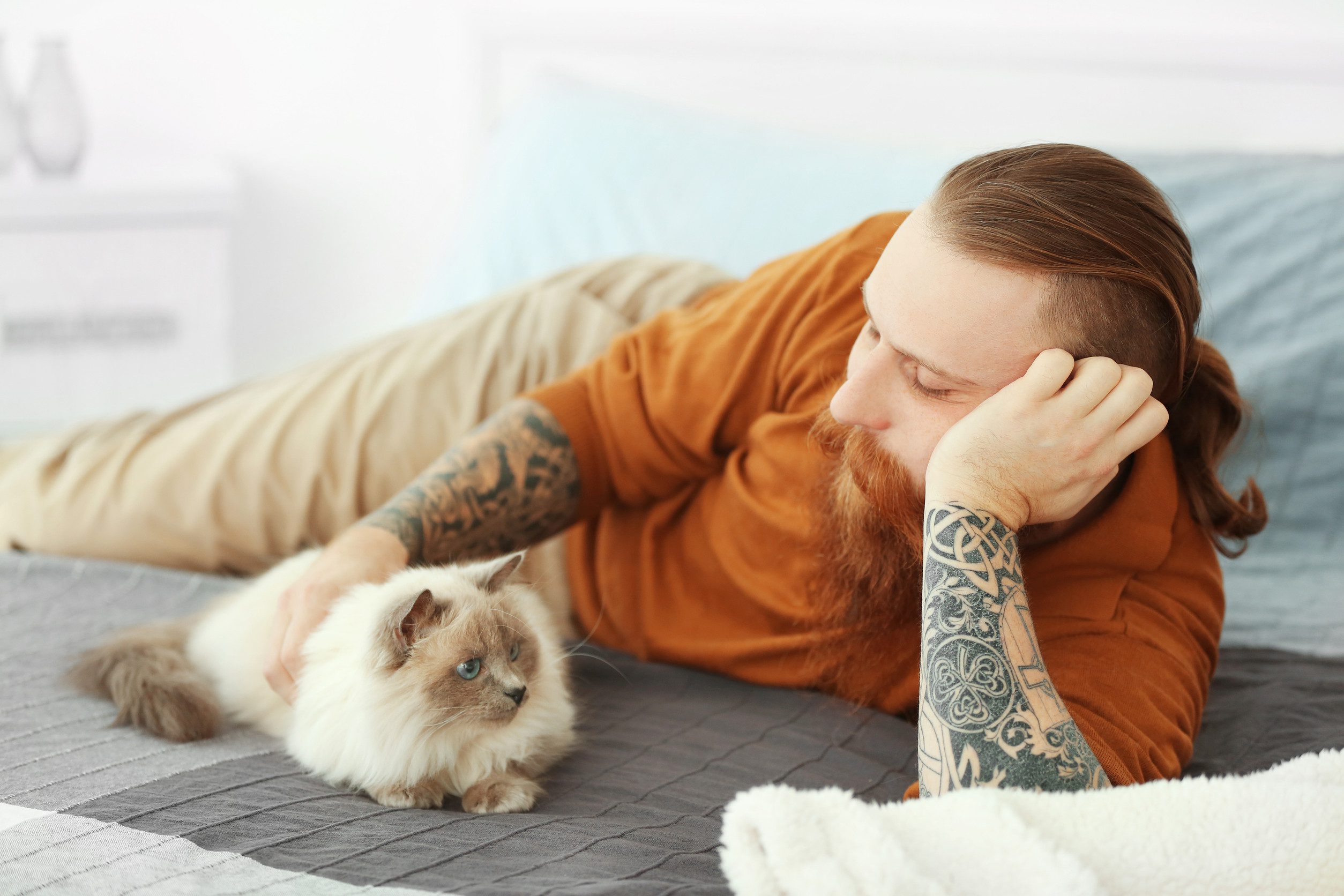 A bearded man with tattoos relaxing next to his emotional support animal in Cedar Rapids, IA.