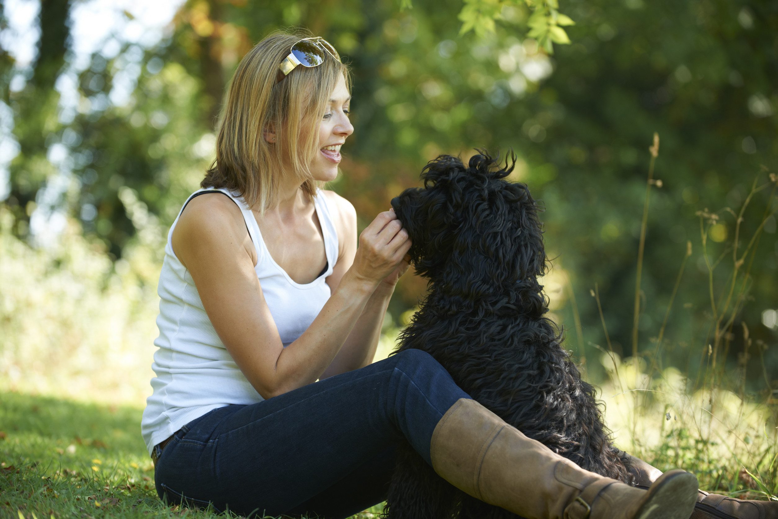 A happy woman spending time with her emotional support animal under the shade of green trees in Overland Park, KS.