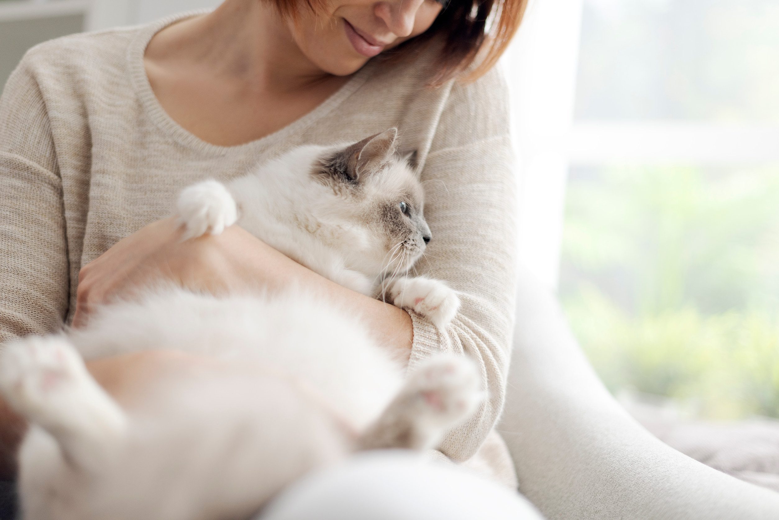 A woman in a beige sweater cuddling her emotional support animal at her home in Wichita, KS.