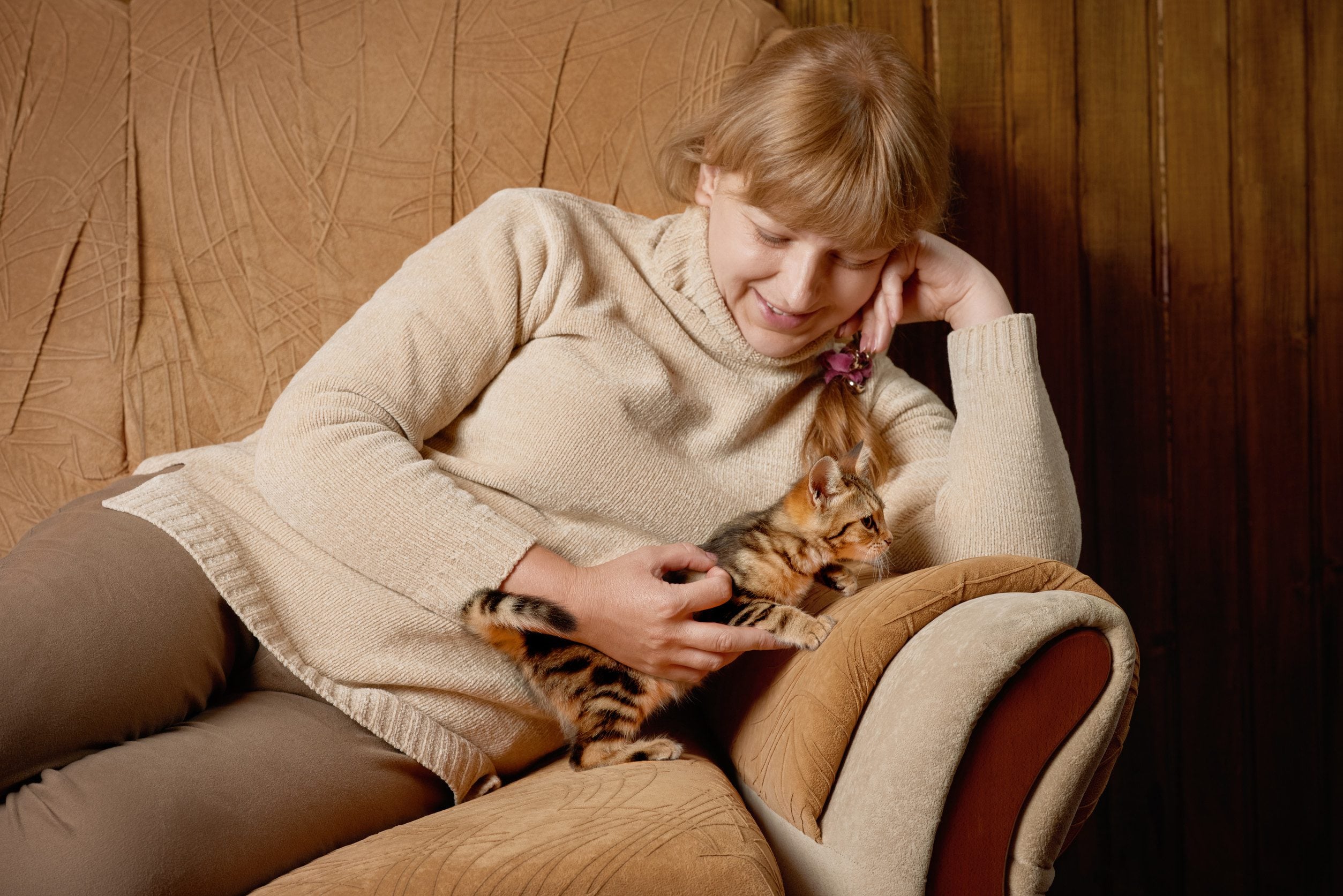 Woman in sweater playing with emotional support animal.