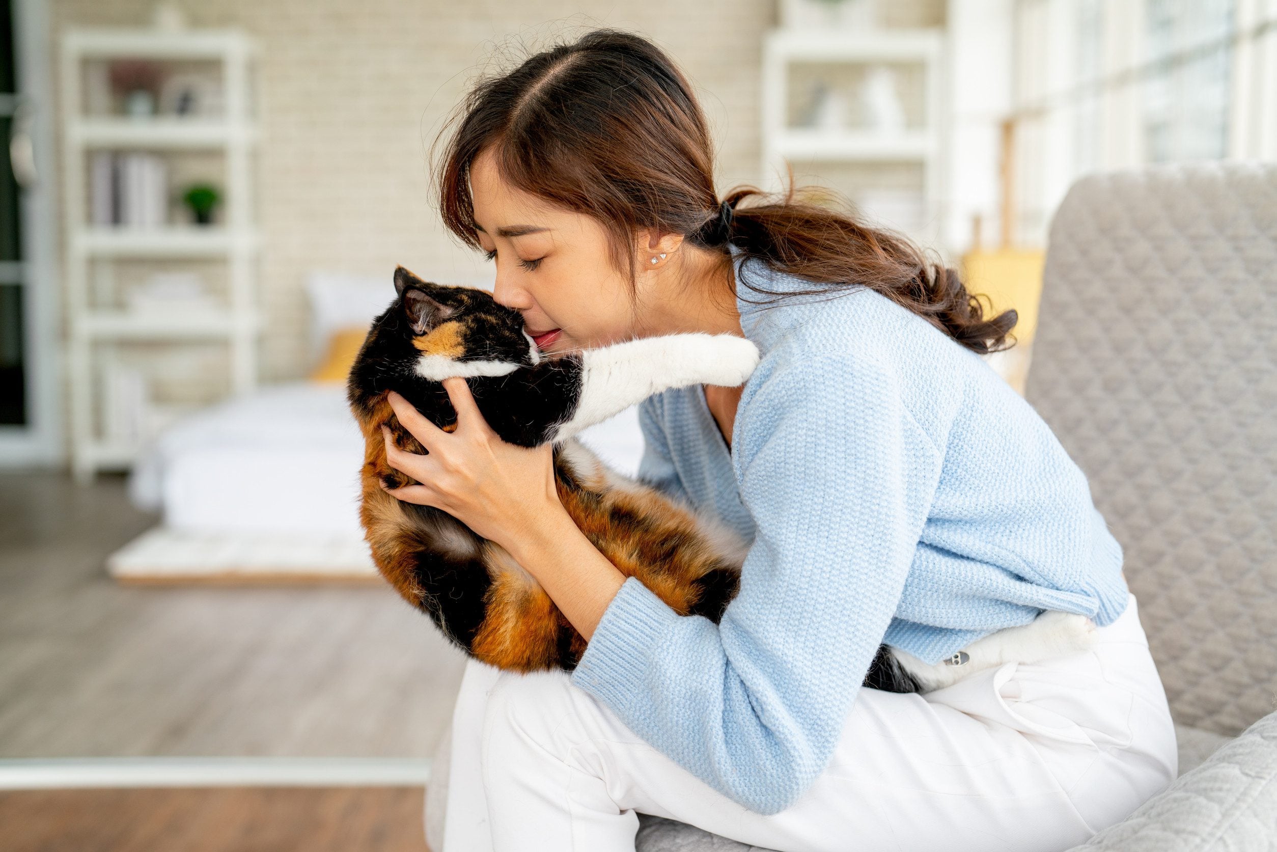 A woman in a pink sweater holding an ESA on her couch in her apartment in Columbia.