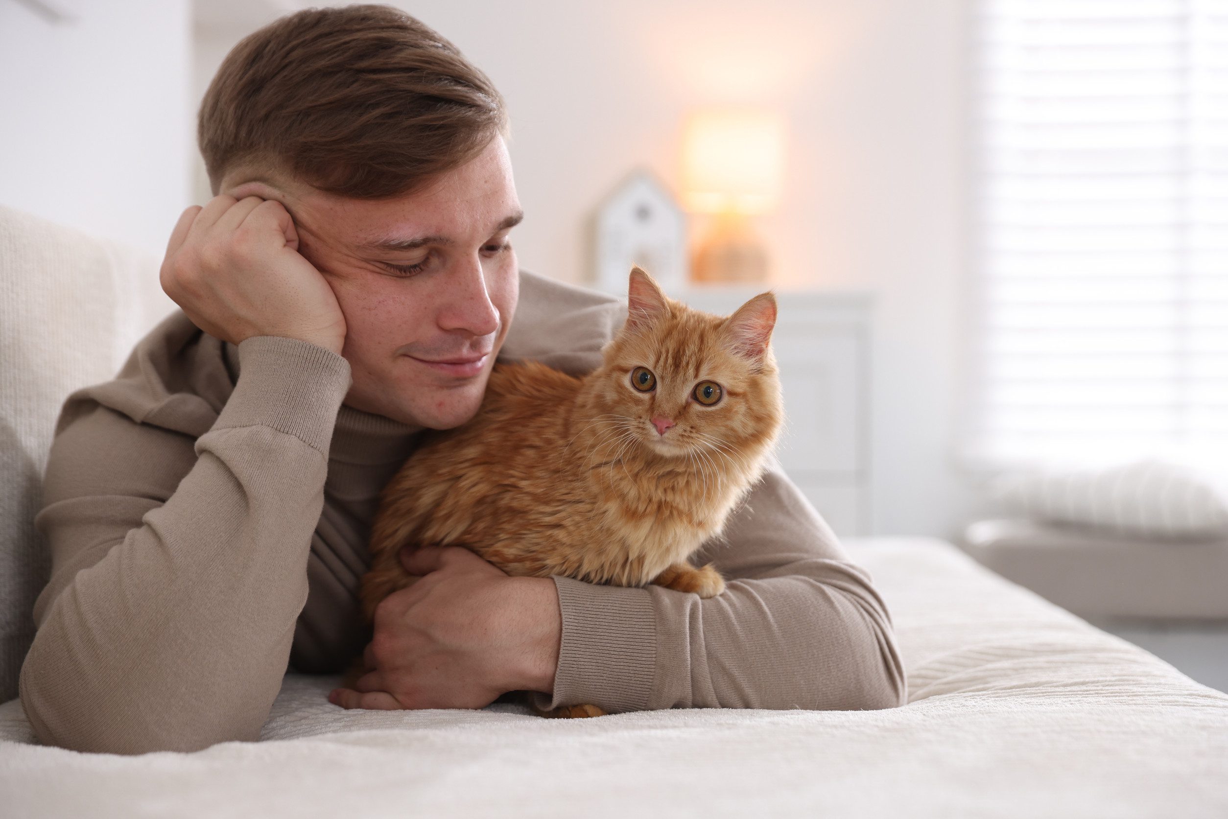 A young man relaxing on his bed while gently holding his emotional support animal in Overland Park, KS.