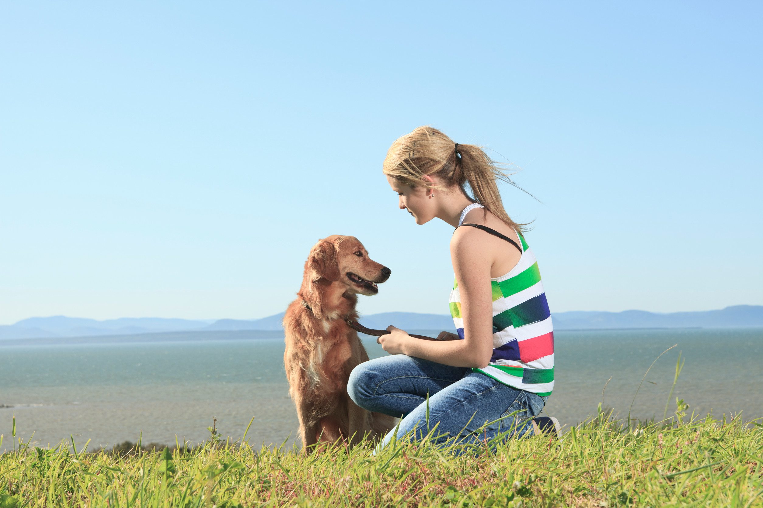 A teenage girl kneeling beside her emotional support animal in Cedar Rapids, IA.