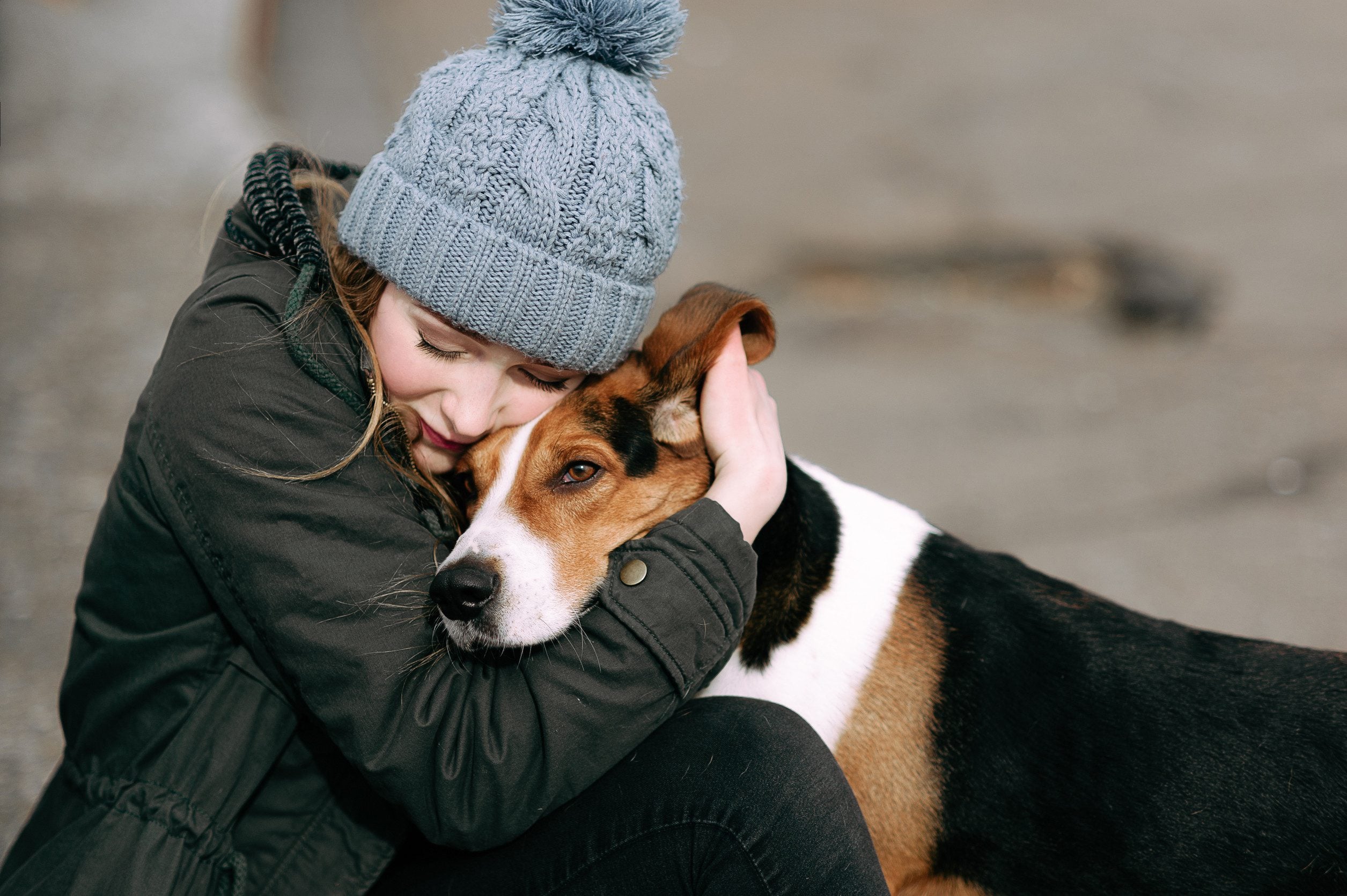 A young girl in a black jacket lovingly hugging her emotional support animal in Warren, MI.