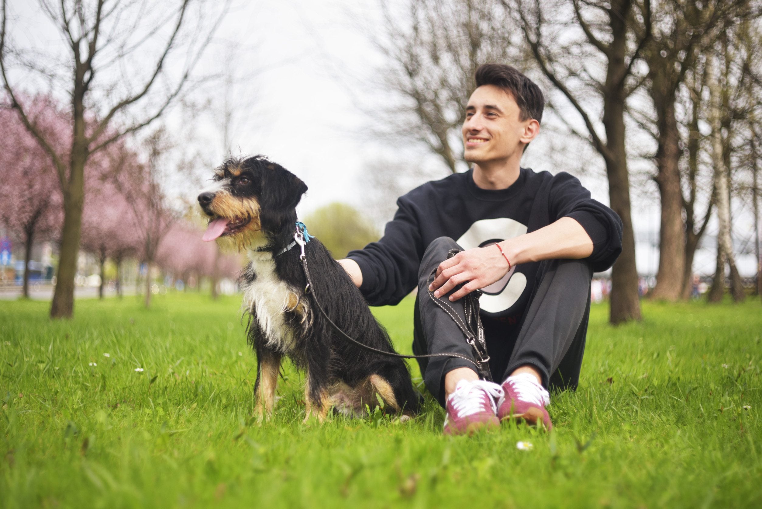A young man sitting with his emotional support animal in a park in Cheyenne, WY.