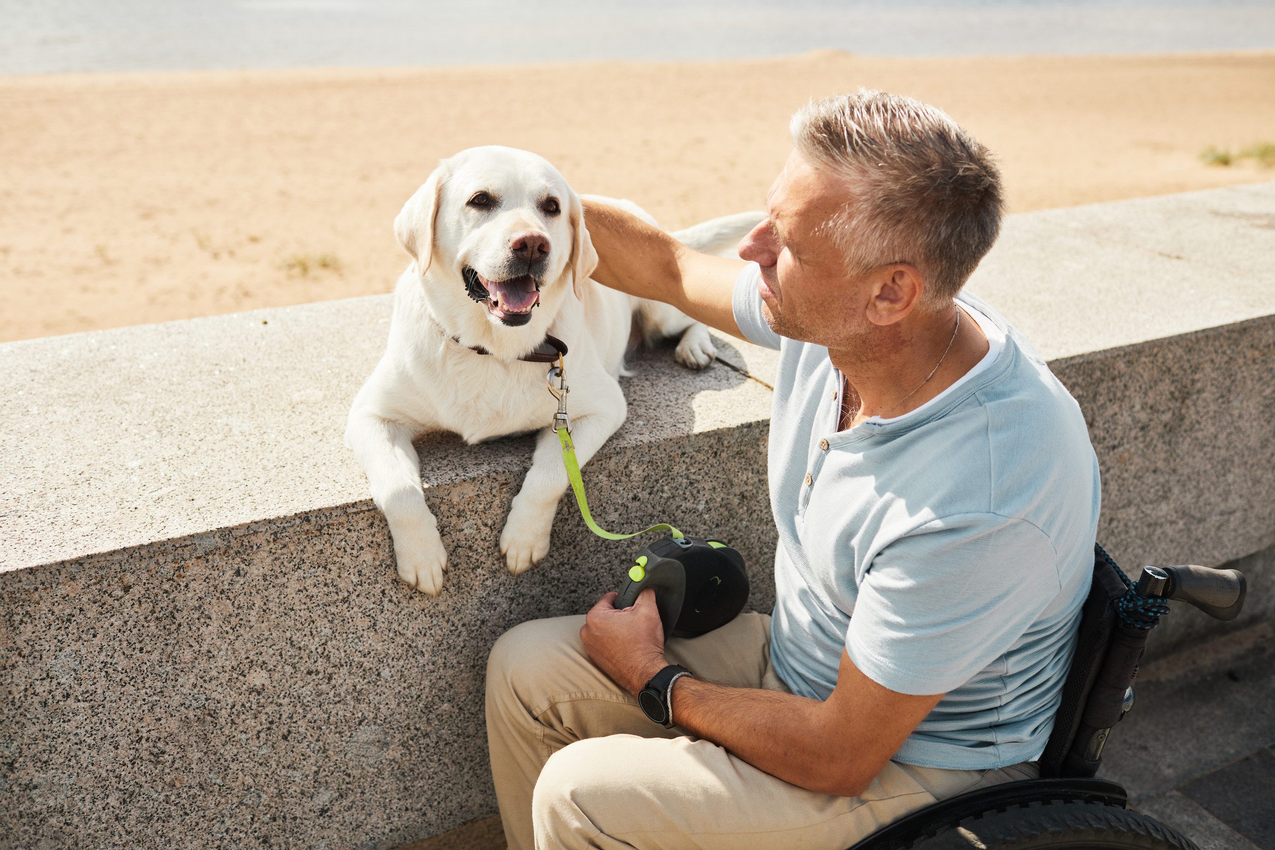 A man in a wheelchair gently petting his emotional support animal in Norman, OK.
