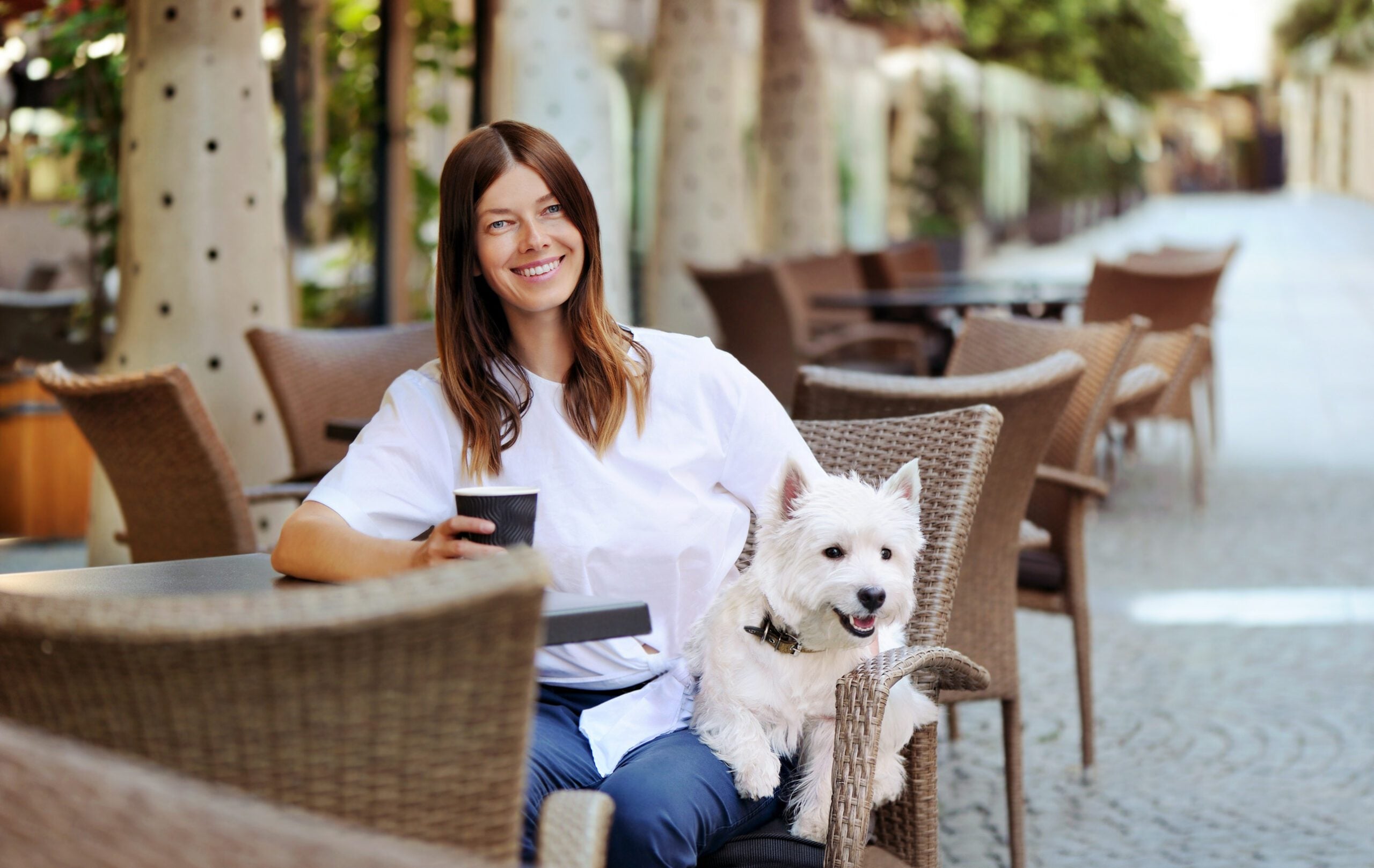 A woman enjoying her cup of coffee at an outdoor cafe with her emotional support animal in Warwick, RI.