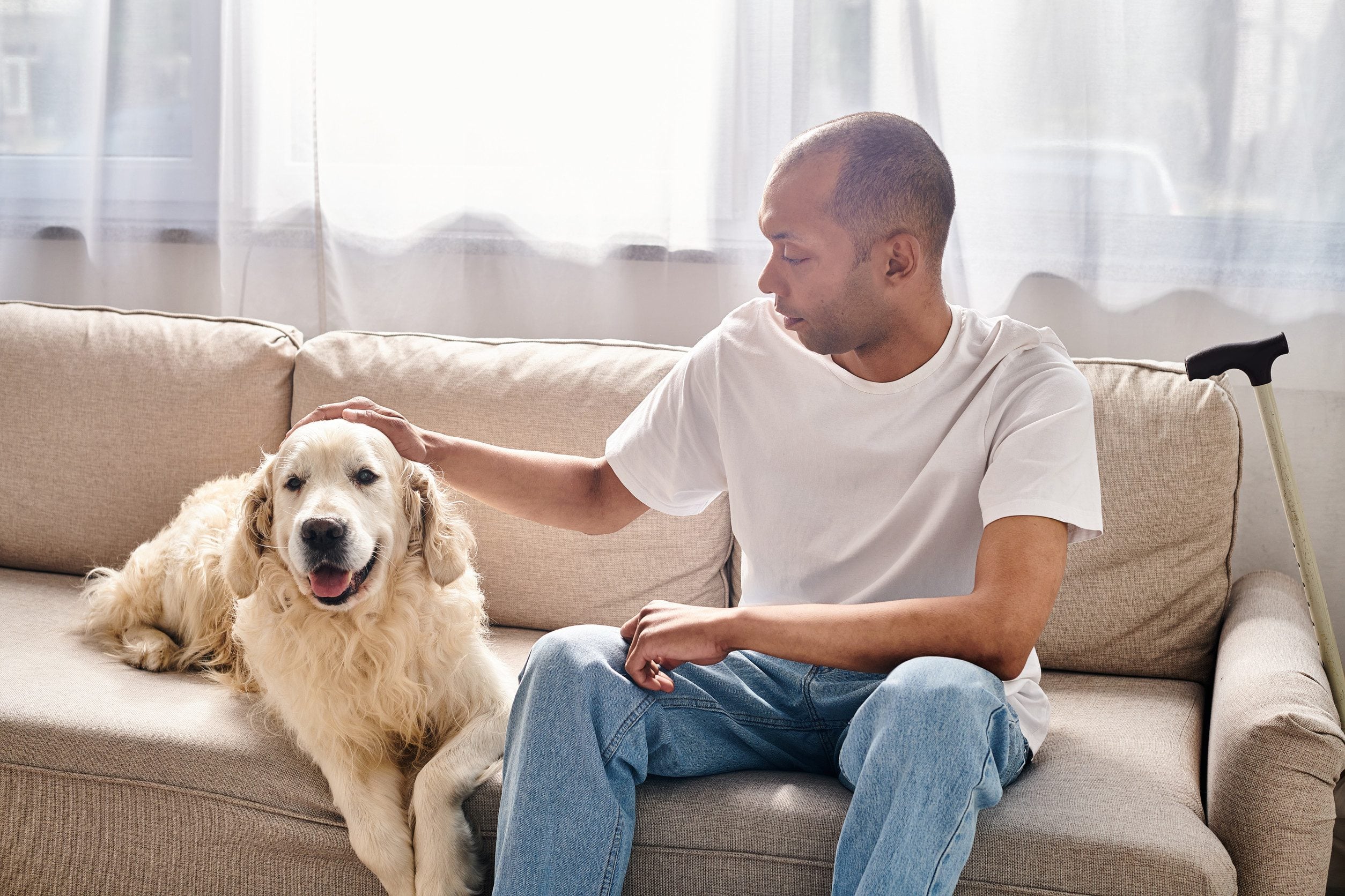 A disabled man sitting on a couch gently petting his emotional support animal in Akron, OH.