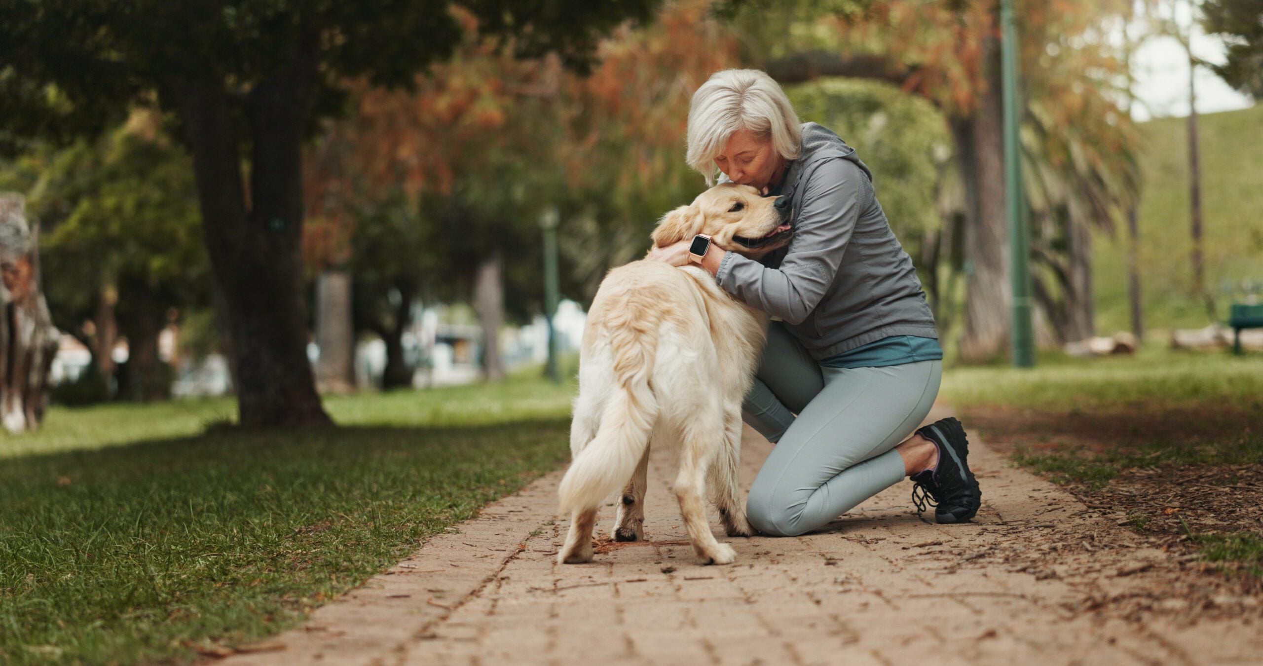 A woman kissing her emotional support animal dog in a park in South Burlington, VT.
