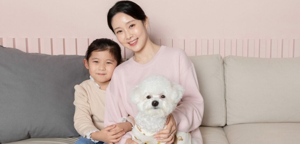 A mother and daughter with a bichon frise, one of the best small dog breeds for families.